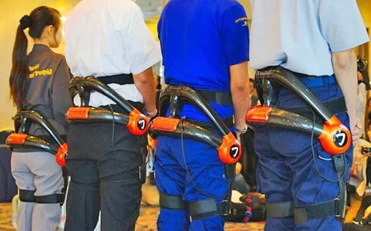 three men and one female airport worker wearing the HAL exoskeleton